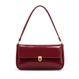 Elva Shoulder Bag with a glossy finish, decorative gold-tone clasp, front flap closure, and shoulder strap.
